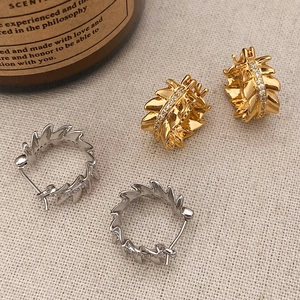 Irregular jagged hoop earrings with inlaid cubic zirconia on textured linen backdrop