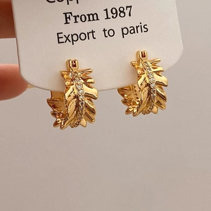 Detail of gold leaf hoop earrings with micro-paved white zircons on a display card