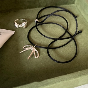 Elegant silver bow pendant necklace and ring set on dark green velvet jewelry box