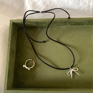 Silver bow pendant necklace with adjustable bow ring set on dark green velvet tray
