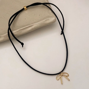 Detail of black suede choker featuring a hollow gold bow pendant and adjustable bead