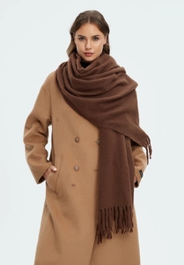 Close-up of thick coffee brown cashmere scarf with fringe paired with a camel coat