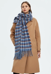 Detail of blue and brown plaid scarf with long tassels on a camel coat background