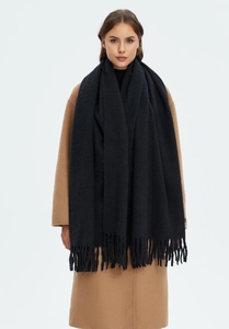 Detail shot of black cashmere-like scarf with fringe on a camel coat model