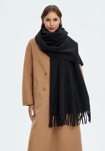 Detail of black cashmere-like scarf with long tassels paired with a camel coat
