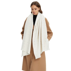 Elegante witte wintersjaal met kleurrijke stippen, gedragen over een bruine jas