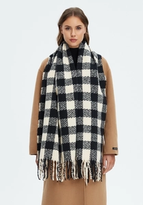 Detailed close-up of a black and white plaid knit scarf featuring long decorative tassels