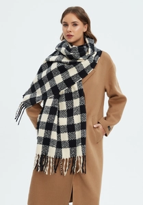 Detailed texture of black and white plaid scarf with fringe on a camel coat