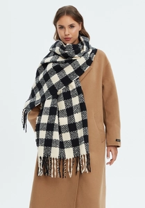 Close-up of black and white checkered scarf with tassel detail on a wool coat