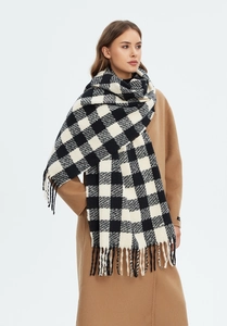 Detail shot of black and white plaid scarf with fringe tassels on camel coat