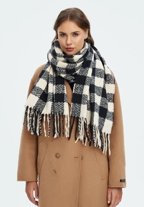 Detail of black and white checkered scarf with long fringe paired with a camel wool coat