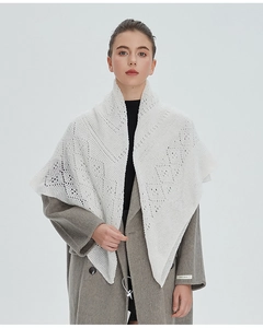 Détail d'un châle triangulaire en tricot dentelle blanc avec des motifs géométriques