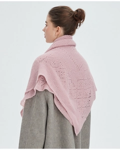 Détail d'une écharpe en laine rose pâle tricotée avec des motifs en losange