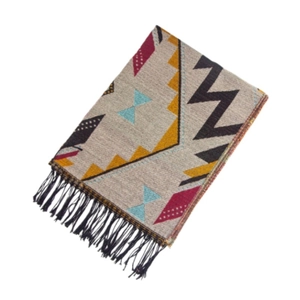 Détail de motifs ethniques tissés et de franges noires sur une écharpe crème