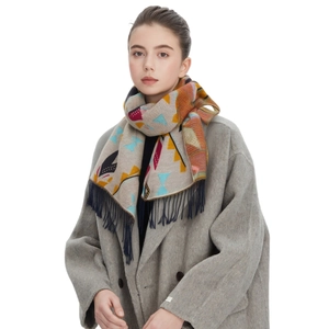 Écharpe d'hiver aux motifs géométriques et franges, portée sur un manteau en laine gris