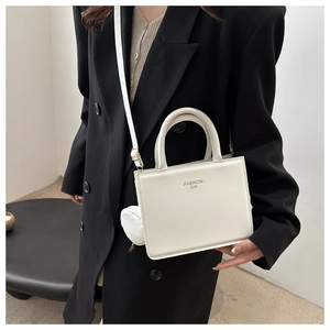 Close-up of white crossbody box bag with Fashion Bag text and heart charm detail