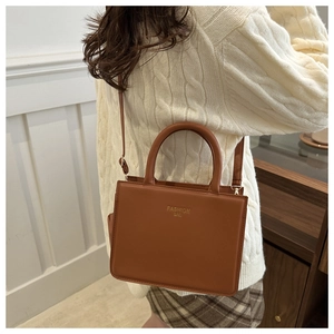 Détail du sac bandoulière en cuir marron avec texte doré et sangle réglable