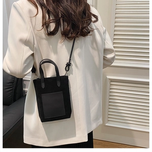Detail of a black mini leopard texture bag with shoulder strap knot on white blazer