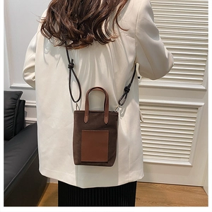 Rear view of a model wearing a mini brown canvas crossbody bucket bag with leather pocket