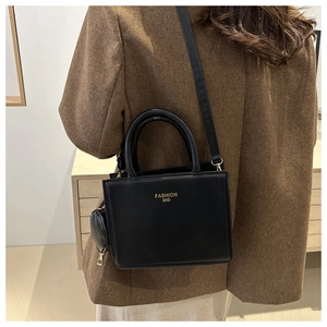 Detail of minimalist black leather crossbody bag with small pouch and gold lettering