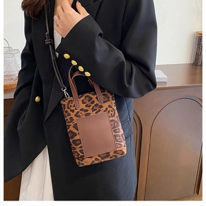 Detail of leopard print mini bucket bag with brown leather handles and shoulder strap