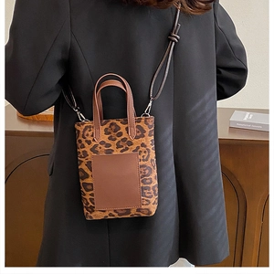 Retro leopard print mini tote with brown handles and adjustable strap on a black blazer