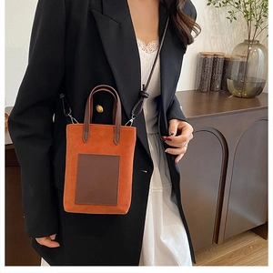 Detail of a mini orange crossbody bucket bag with brown straps and textured matte finish