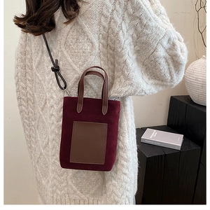 Detail of burgundy velvet crossbody bag with brown leather pocket on knit sweater