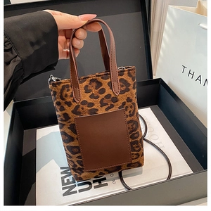 Close-up of leopard print mini bucket bag with faux leather pocket and top handle