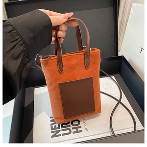 Mini orange suede bucket bag with brown leather handles placed in a luxury gift box setting