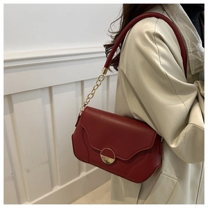 Detail of burgundy leather shoulder bag with gold metal ring buckle and chain strap