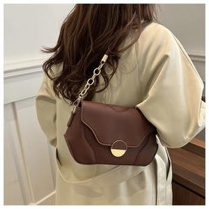 Detail of a dark brown half-moon underarm bag with gold metal buckle and leather chain