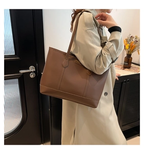 Close-up of a large dark brown leather tote bag with elegant vertical stitching details