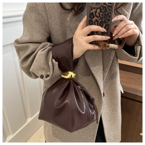 Détail du sac seau plissé marron foncé avec une poignée décorative en boule dorée