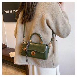 Détail d'un sac vintage vert foncé avec fermoir métallique et pendentif en corde