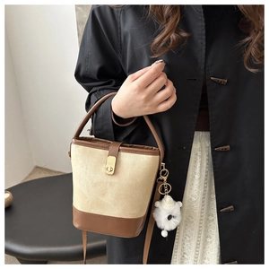 Detail of vintage bicolor bucket bag with gold lock and white plush pendant accessory