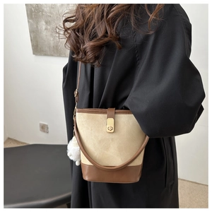 Detail of canvas bucket bag with brown leather trim and cute white plush pompom charm