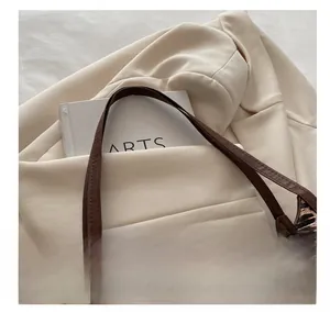 Détail d'un sac à main léopard avec poignée en cuir marron et boucle en métal doré