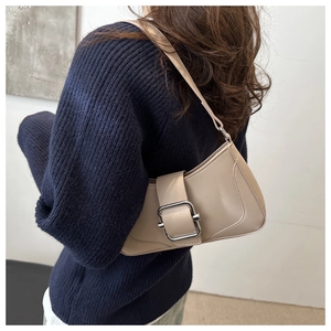 Detail of beige shoulder bag with silver buckle and decorative stitching on a model