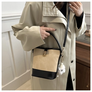 Detail view of contrast bucket bag with beige suede, black leather trim and plush charm