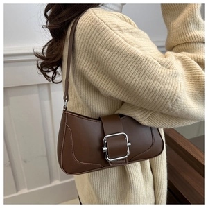 Detail of a dark brown smooth leather baguette bag worn over the shoulder with a beige sweater