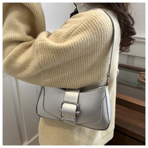 Gros plan détaillé d'un sac à bandoulière argenté avec une grande boucle carrée