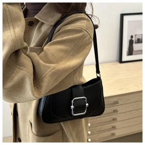 Sac baguette noir en cuir avec boucle argentée porté à l'épaule par un mannequin