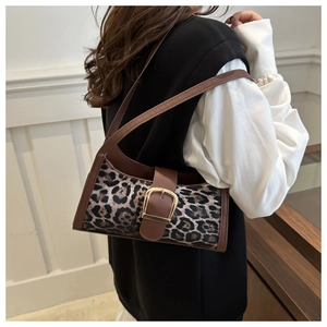 Detail of leopard print baguette bag with golden metal buckle and brown leather trim