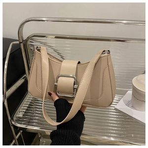 Detail of beige leather shoulder bag featuring a large silver square metal buckle accent
