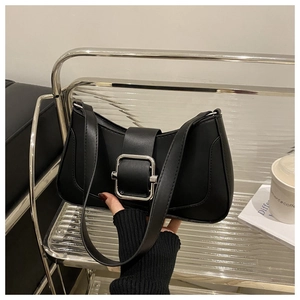 Detail of elegant black shoulder bag featuring a prominent square silver metal buckle