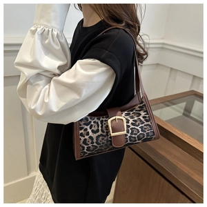 Detail einer Schultertasche mit Leopardenmuster, großer Goldschnalle und braunem Rand