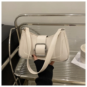 Detail of a creamy white shoulder bag featuring a silver square buckle and smooth faux leather
