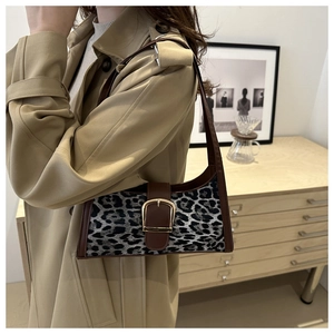 Dettaglio borsa baguette leopardata con fibbia a ferro di cavallo su modella in trench