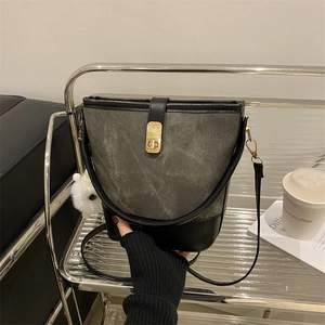 Chic winter bucket bag in grey-green and black leather with gold clasp and fur charm
